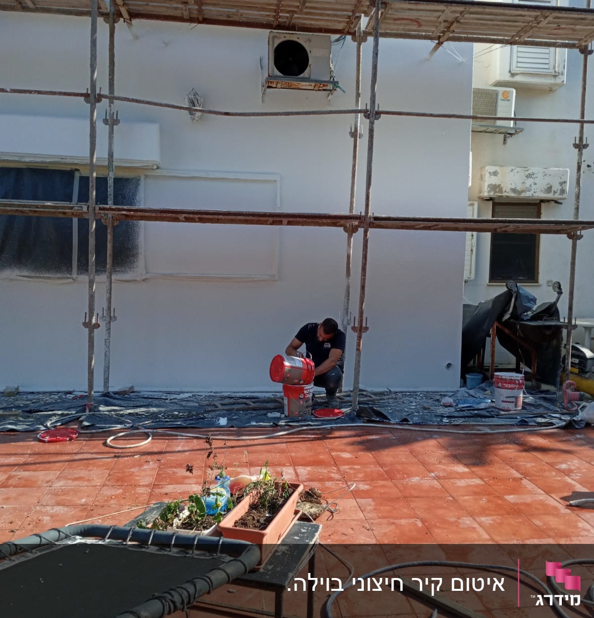 פיגומים, פועל עם דלי צבע, קיר צבוע, צינורות על הרצפה